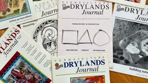 Permaculture Drylands Journals spread out on a table.